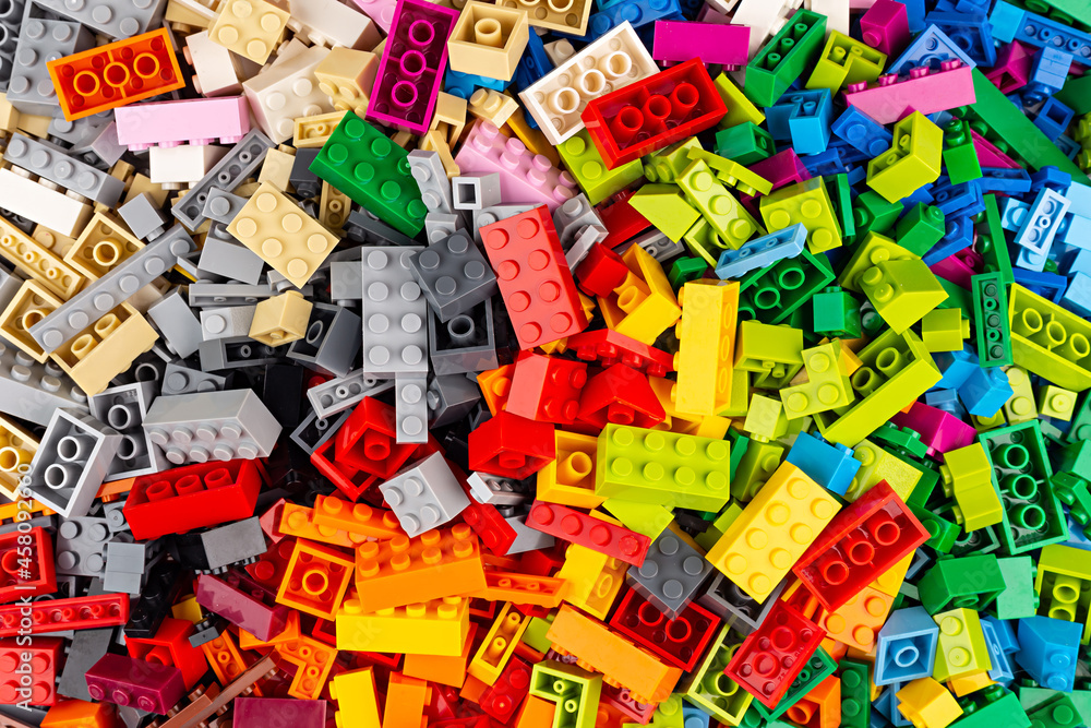 close-up of huge pile of stackable plastic toy bricks top view.  Colorful texture childhood education and development concept background.