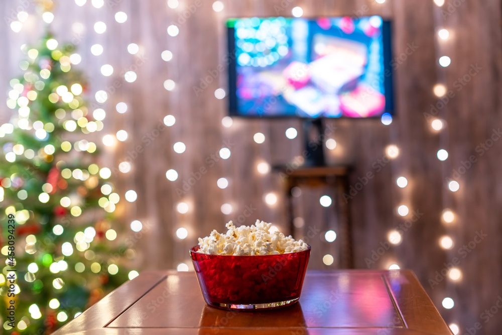 Christmas eve. Red bowl with popcorn on the table. Home cinema. Tv. Cropped, close up
