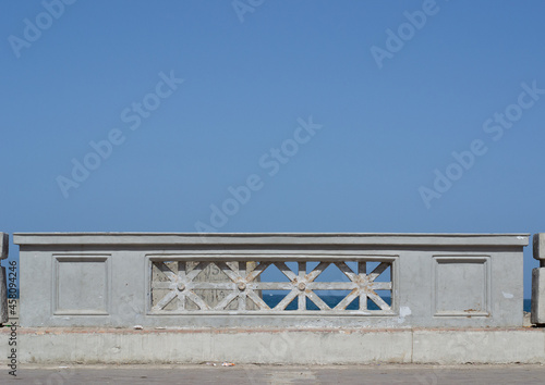 Cement fence separating the road from the Mediterranean sea in Alexandria, Egypt with a blue sky and copy space