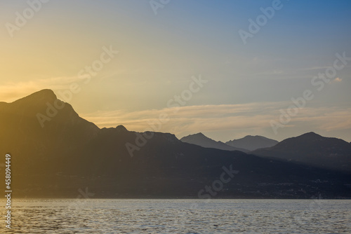 Italy - Lake Garda in the town of Torri del Benaco. A sunset, a romantic place by the water, with mountain peaks in the distance. © Grzej