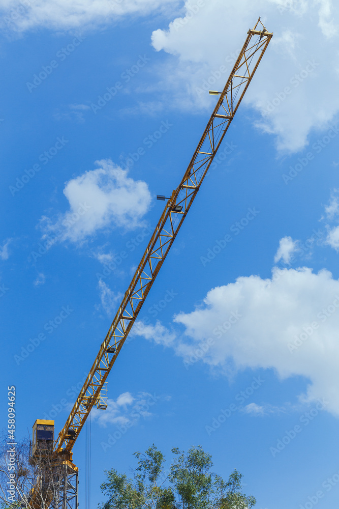 The boom of a construction crane on the background of a blue sky The boom of a construction crane on the background of a blue sky