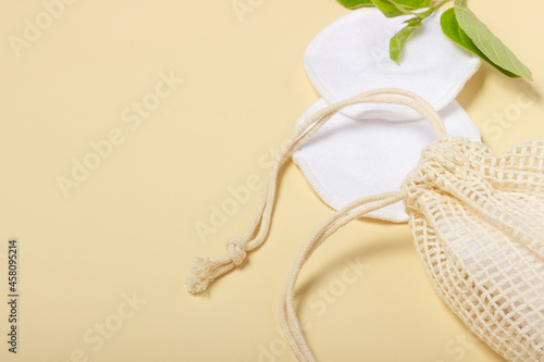 Cotton reusable makeup remover pads in a cloth bag on a beige background. The concept of ecology and conscious consumption. Reusable cotton pads