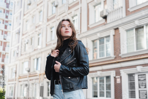 young woman in black turtleneck and leather jacket on urban street of europe