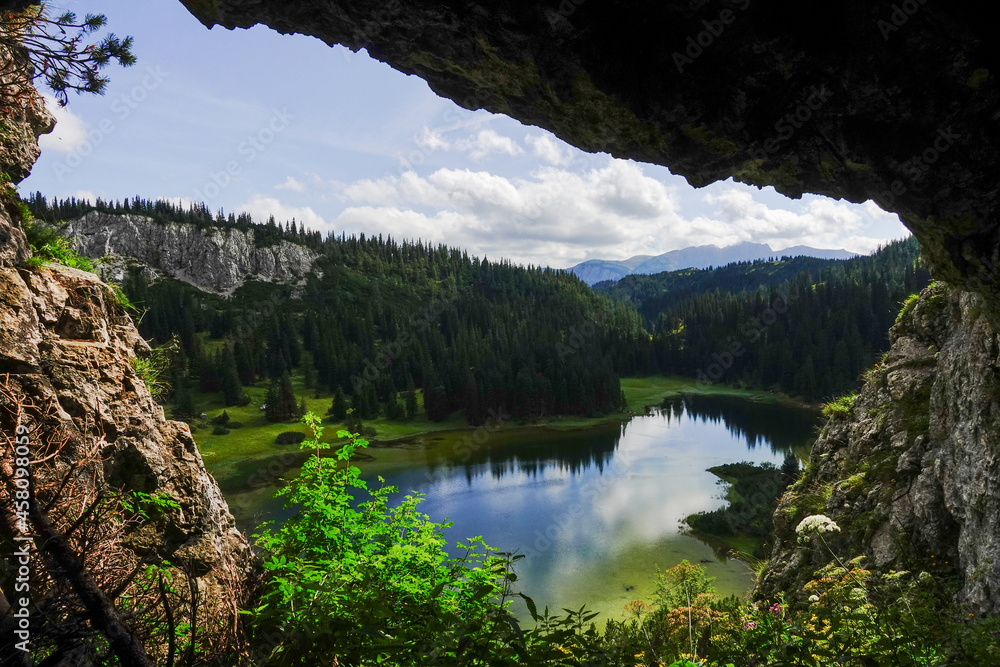 view from a cave to a amazing blue mountain landscape with reflections