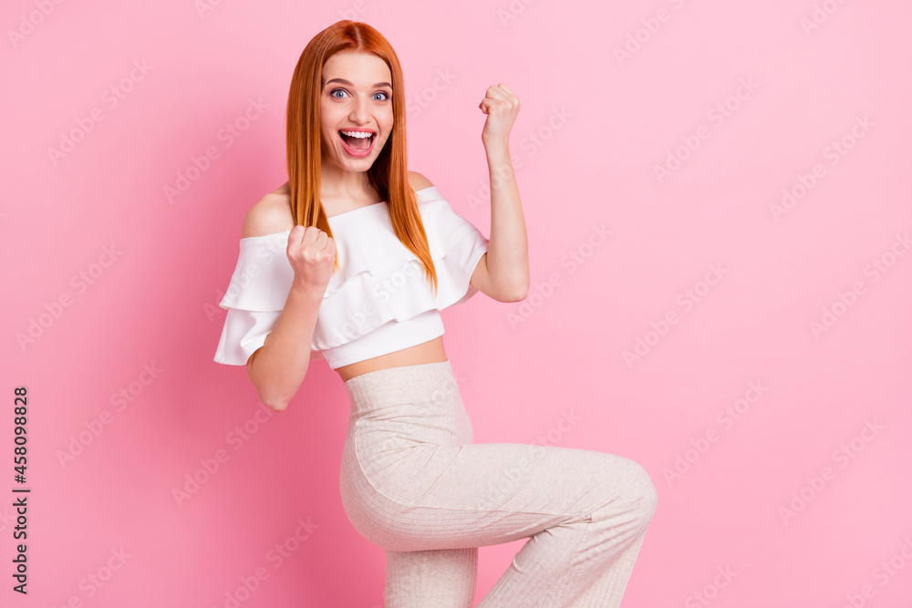Photo of cheerful happy young nice woman winner raise fists good mood smile isolated on pink color background Photo of cheerful happy young nice woman winner raise fists good mood smile isolated on pink color background