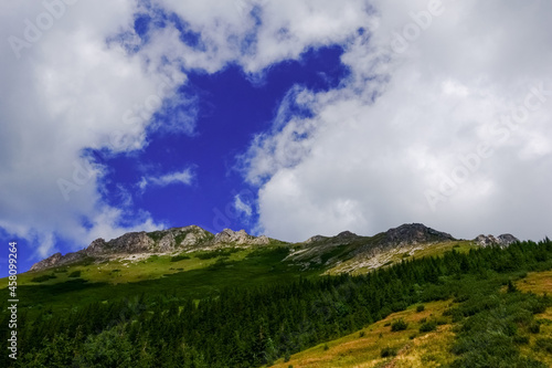 wonderful mountain with green places and white clouds on blue sky