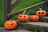 Pumpkins with carved faces and various emotions stand on the steps of an old wooden staircase near the house. Traditions of celebrating Halloween. Surprised, laughing, angry, squinting pumpkins