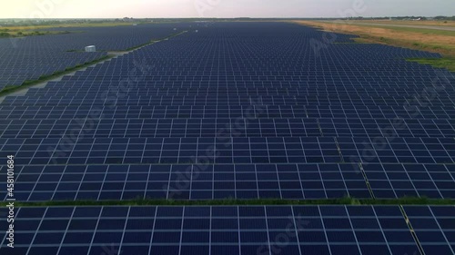 Drone close up flies over large solar panels at a solar farm at sunny summer evening. Solar cell power plants, green grass. Footage video 4k.