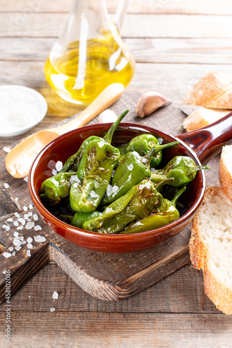 Grilled pepper Padron in a frying pan on a table. Spanish cuisine. Pimientos de Padron