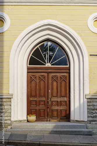 Wooden door over white stone arch and flower pot. © josemiguelsangar