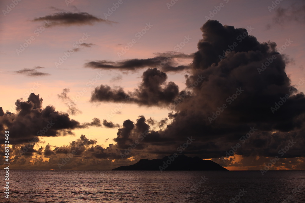 Sunset on the sea with a pink blue sky and a black cloud over the island on the horizon Sunset on the sea with a pink blue sky and a black cloud over the island on the horizon