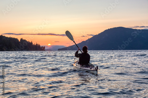 Adventurous Woman on Sea Kayak paddling in the Pacific Ocean. Colorful Sunset Sky. Taken near Victoria, Vancouver Islands, British Columbia, Canada. Concept: Sport, Adventure