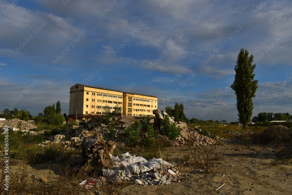 a yellow, lonely, abandoned, old, office building and a construction debris dump in front of it a yellow, lonely, abandoned, old, office building and a construction debris dump in front of it