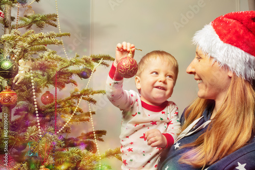 Mother and little toddler decorate Christmas tree © Sergey Novikov