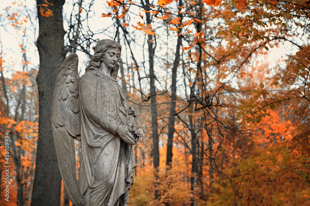 Angel statue on old cemetery, autumn natural background. Design for condolences, mourning cards or obituary. concept of religion, faith, Remember, mourn, memory.