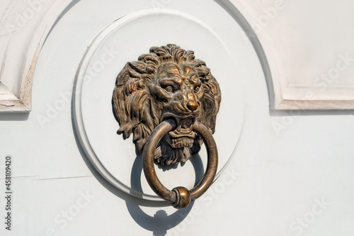 Decorative door handle in form of lion head on white rustic wooden background. Door knocker with lion