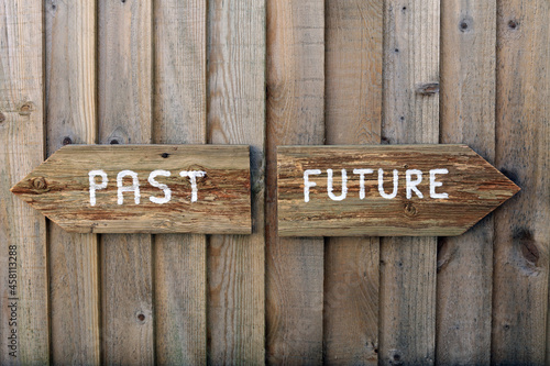 past and future directional wooden signs on a wood panel fence