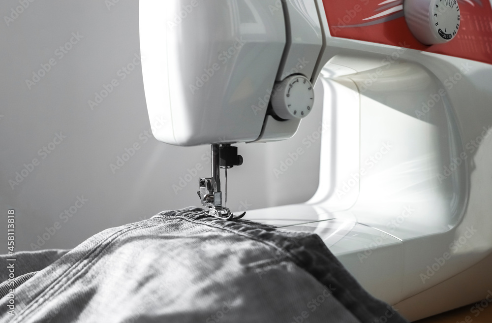 Denim cloth on sewing machine close up. Small business concept.