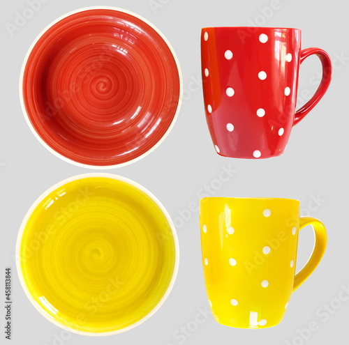 Two pairs of different colours — red and yellow cups and plates isolated on light gray background photo