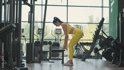 Hispanic woman performing barbell bent over row. Fitness woman training Bent-Over Row aka Bent Over Row aka Barbell Row. Train your back muscles with a barbell while standing in a tilt photo