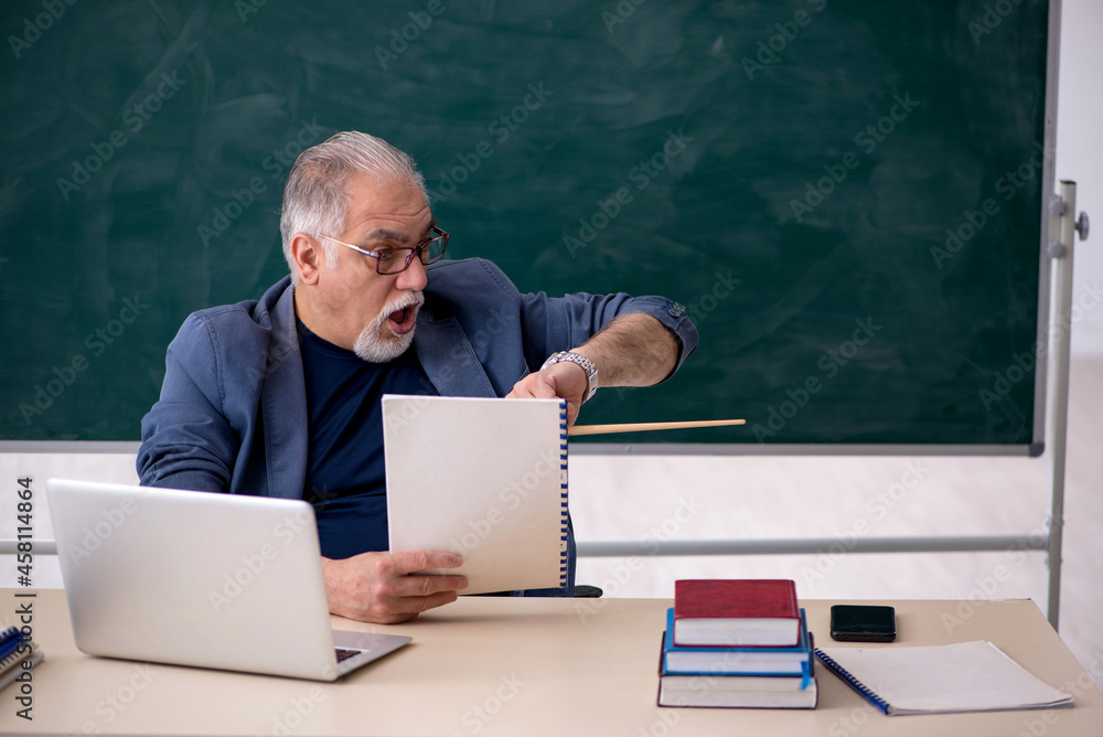 Old male teacher in the classroom Old male teacher in the classroom