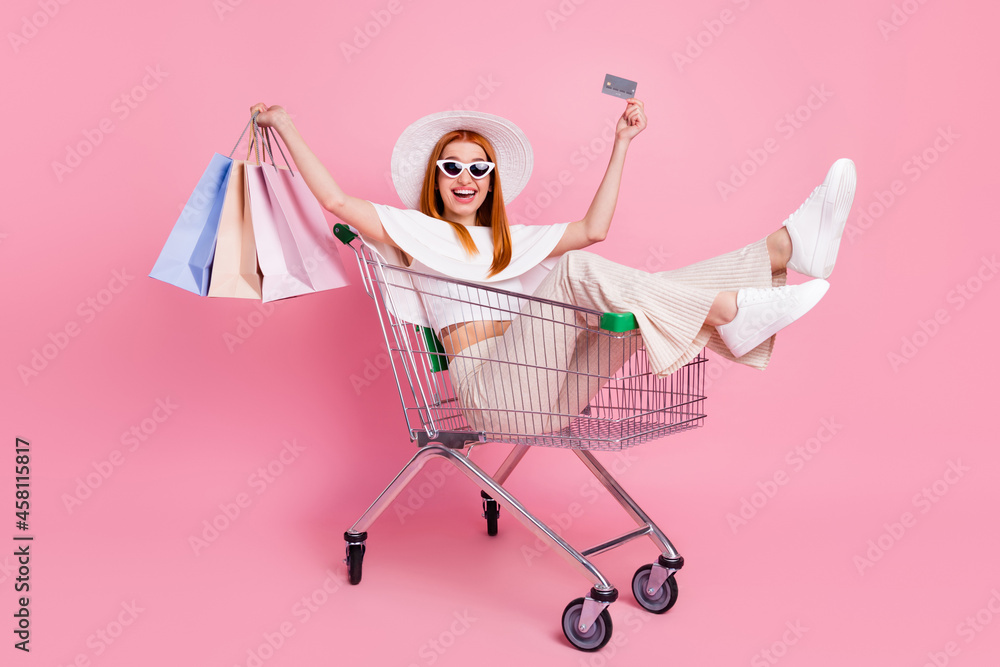 Φωτογραφία Portrait of beautiful trendy fashionable cheerful girl riding in cart holding ba