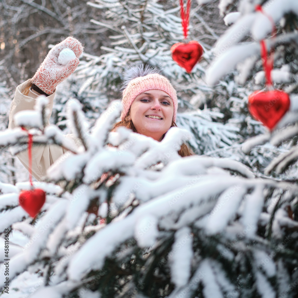 Woman playing snowballs by the christmas tree in winter nature on new year's eve