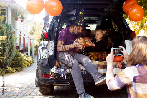 Family celebrating Halloween car trunk. Having fun together. Autumn