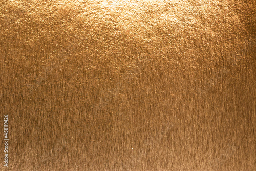 Textured metallic gold background with light and dark highlights, bright and shiny golden metal texture