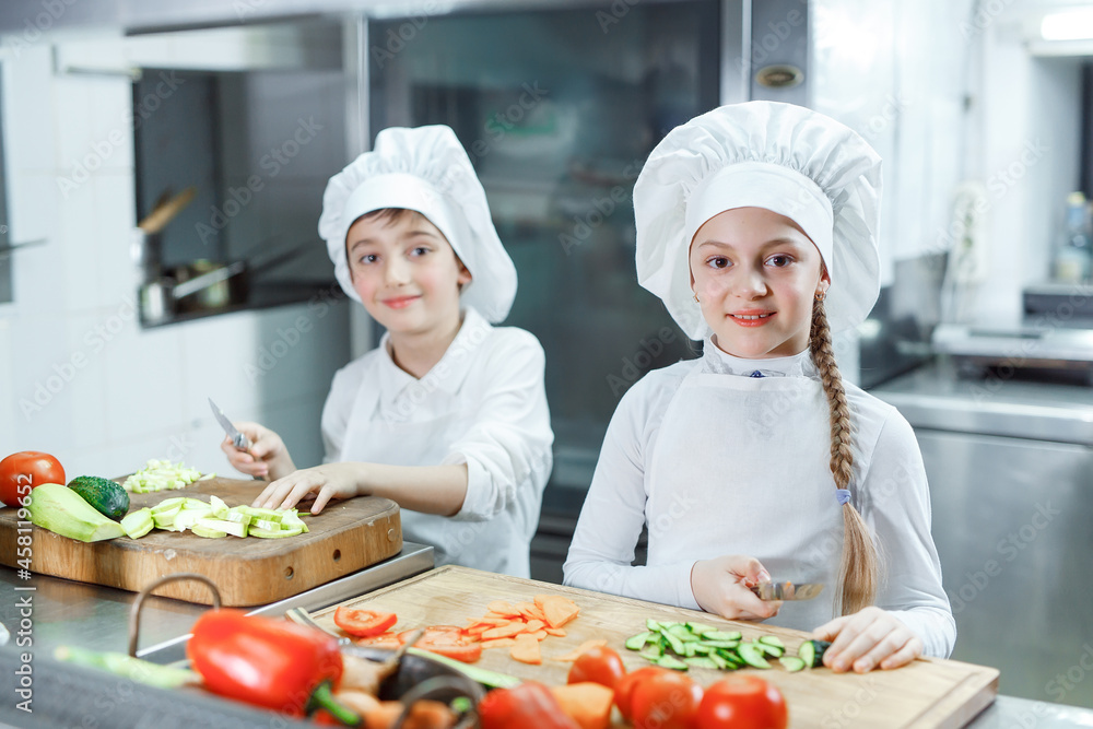 Children grind vegetables in the kitchen. Children grind vegetables in the kitchen.