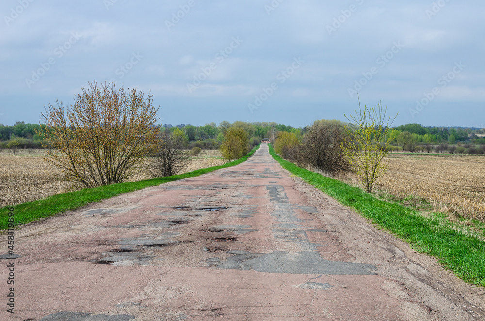 Obraz premium Damaged asphalt road with potholes. Dangerous asphalt road with holes destroyed