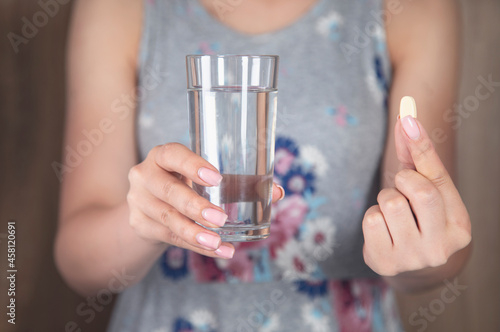 Female holding a glass of water and drug