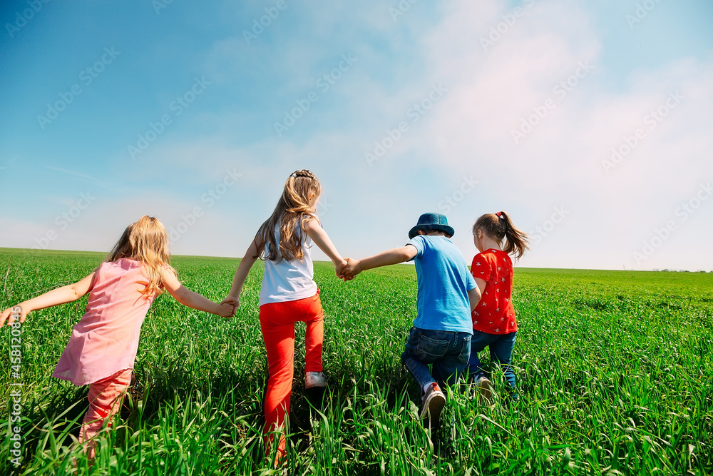 Kids friends run across a green field. View from the back. Kids friends run across a green field. View from the back.