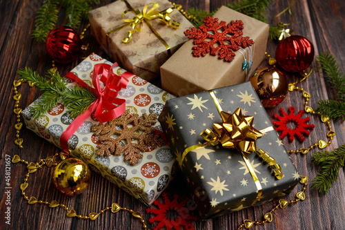 View of red and gold gift boxes against the background of Christmas decor on a wooden table. The concept of preparation for Christmas and New Year