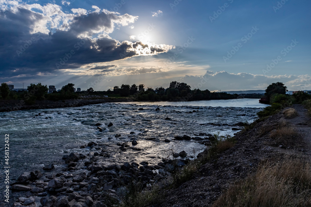 Beautiful sunset over Sava river rapids in Zagreb city, with storm clouds approaching fast, bringing heavy rain