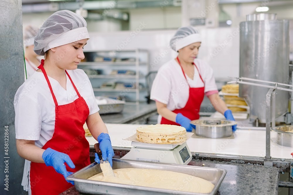 Decorating cakes on the conveyor of a confectionery factory. Decorating cakes on the conveyor of a confectionery factory.