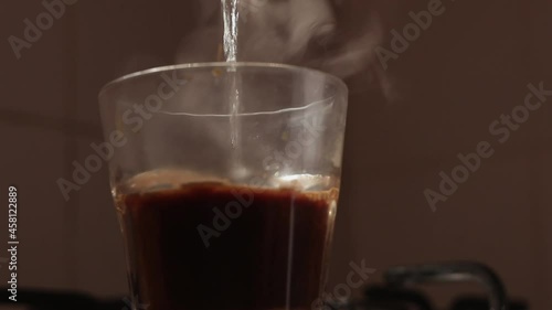 Photo of a person pouring hot water into a glass of coffee
