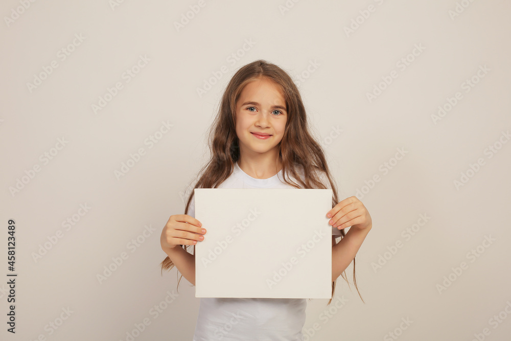 a beautiful sweet happy girl with long hair in a white T-shirt is holding a white sheet in her hands a beautiful sweet happy girl with long hair in a white T-shirt is holding a white sheet in her hands