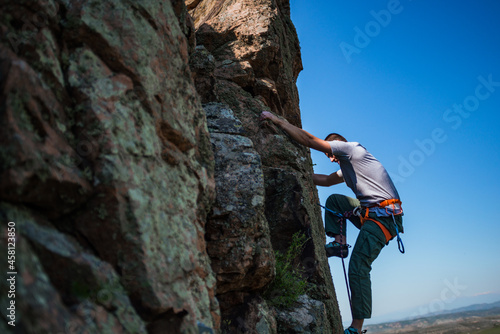 Young handsome sportsman climbing up a rock cliff
