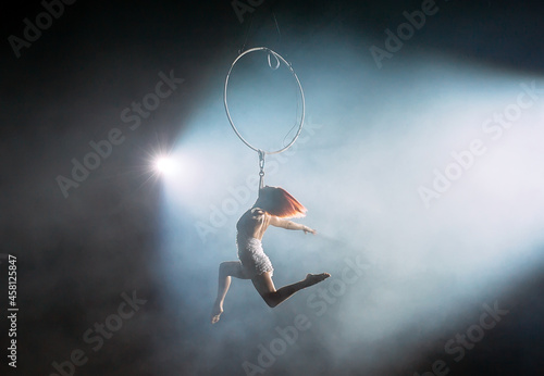 Aerial acrobat in the ring. A young girl performs the acrobatic elements in the air ring. © davit85