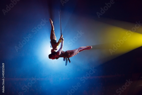 Circus actress acrobat performance. Two boys perform acrobatic elements in the air. photo