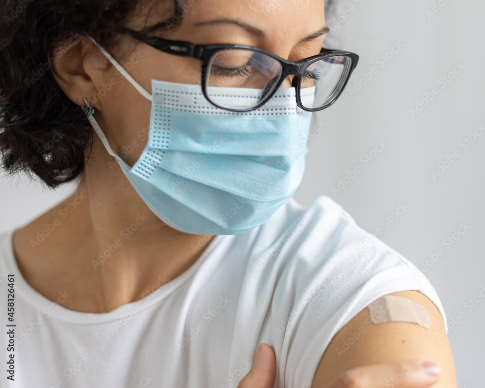 young woman in mask with plaster on her shoulder, after vaccination young woman in mask with plaster on her shoulder, after vaccination