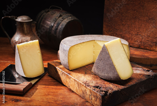 Canvas Print Traditional aged mountain cheese of the Alps offered as loaf and piece at a rust