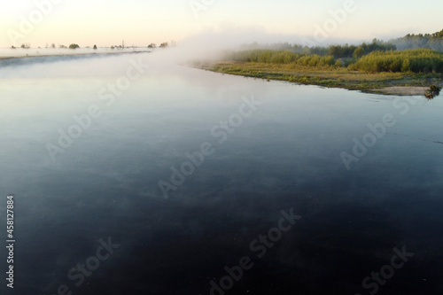 Mist covers the river  trees  and land at dawn. Autumn photos of fog taken with drone