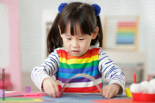 young girl making paper rainbow craft for homeschooling