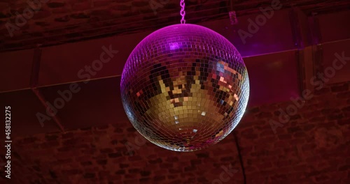 disco ball weighs under the ceiling, reflecting surfaces in neon light. retro style.