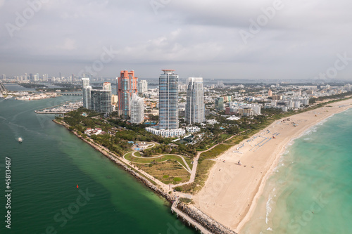 Incredible daytime aerial view of South Pointe high-rise condominiums looking down Miami Beach with sandy shores lining the turquoise waters of the Atlantic Ocean with cloudy sky above. © Joseph Kirsch