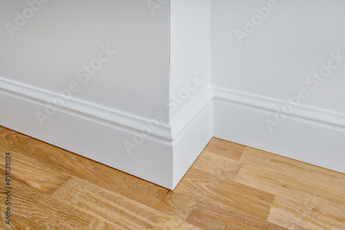 Fototapeta Detail of corner flooring with intricate crown molding and plinth