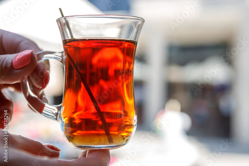 A transparent cup with Turkish tea in her hands.