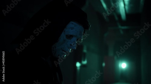 Maniac in mask holding axe portrait, standing in dark corridor. Mystical scary murderer going to kill, carrying murderous weapon. Halloween costume of killer. Horror scene or nightmare concept. 